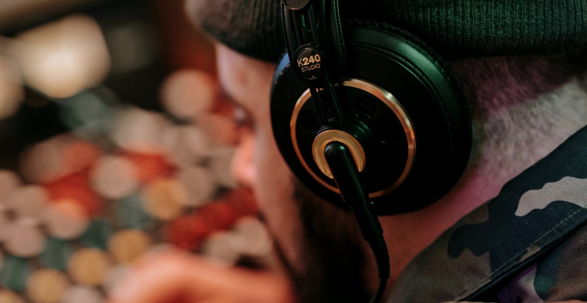 A listener wearing studio headphones at a mixing console